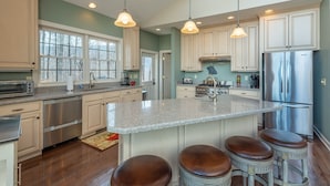 A spacious kitchen with granite countertops, stainless steel appliances, and a central island with bar stools. - Hummingbirds' Mountain Retreat | Hot Tub, Game Room, Home Office & Mountain Views! (Old Fort)
