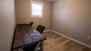 Une pièce avec une table en bois, deux chaises, une fenêtre et des murs de couleur claire.