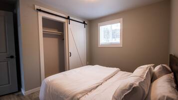 A bedroom with a bed, a sliding closet door, and a window.