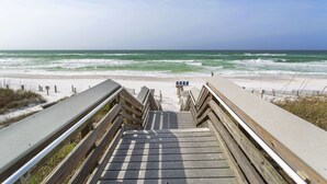 Eine Holztreppe führt zu einem Strand mit Blick auf das Meer.