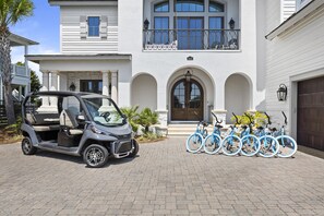 A compact car parked in front of a white building with a large arched entrance and a balcony.