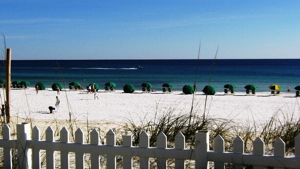 A beach with white sand, clear blue sky, and green umbrellas. - 5 minute to the public beach (Destin)