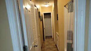 A narrow hallway with a tiled floor, white doors, and a light fixture on the ceiling. - 5 minute to the public beach (Destin)