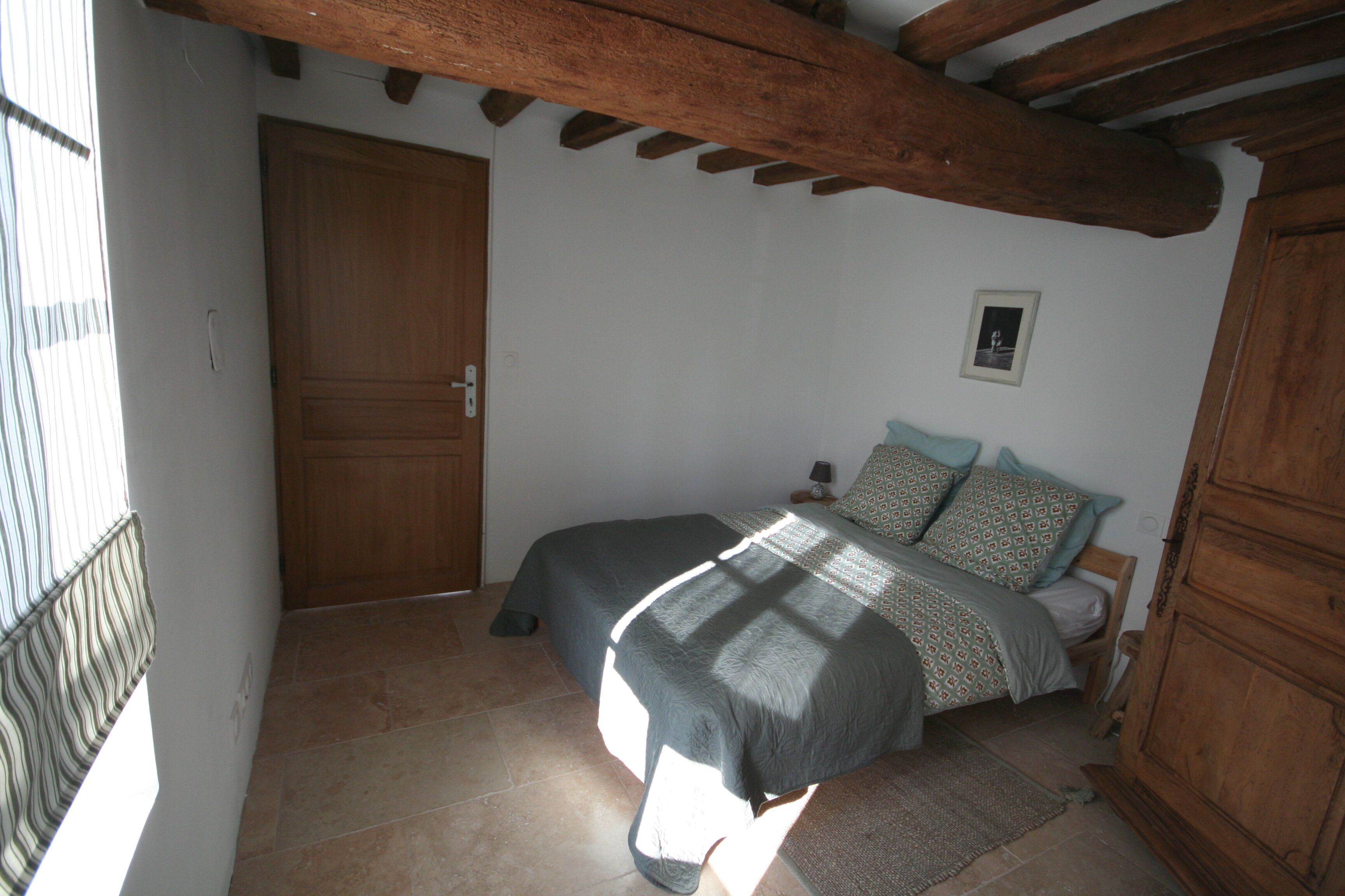 Ein Schlafzimmer mit Bett, Holzschrank und Tür.