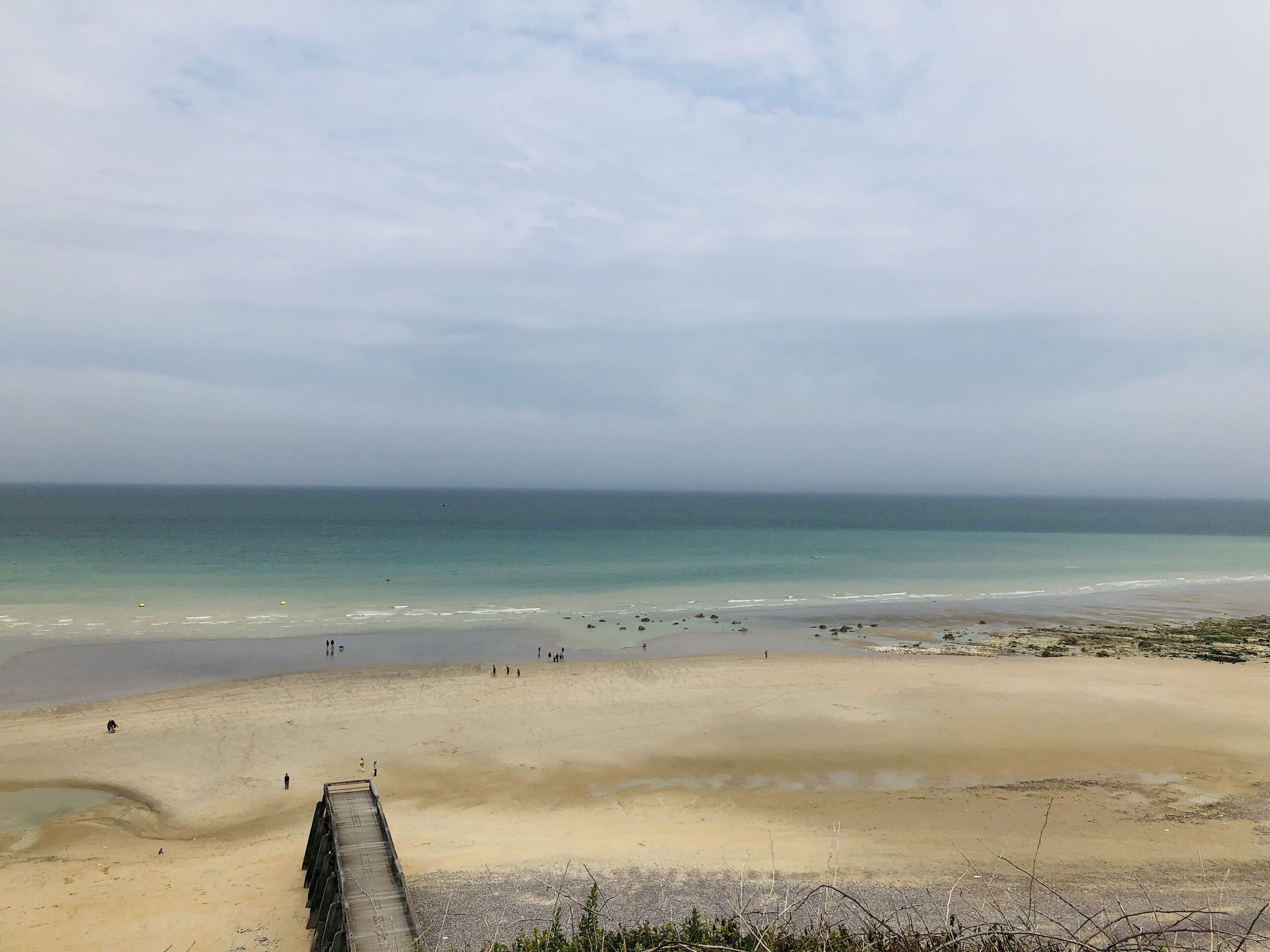A beach with a wooden walkway leading to the shore.