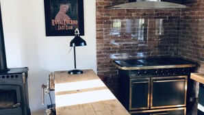 Une cuisine équipée d’un poêle à bois, d’une cuisinière à gaz moderne et d’un mur en briques.