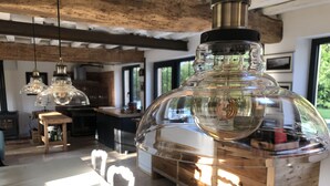 Une cuisine moderne avec un grand vase en verre transparent comme élément central, des meubles en bois et un plafond rustique.