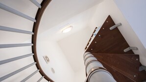 A spiral staircase with a wooden handrail and white walls. - Casa Greta (San Vito Lo Capo)