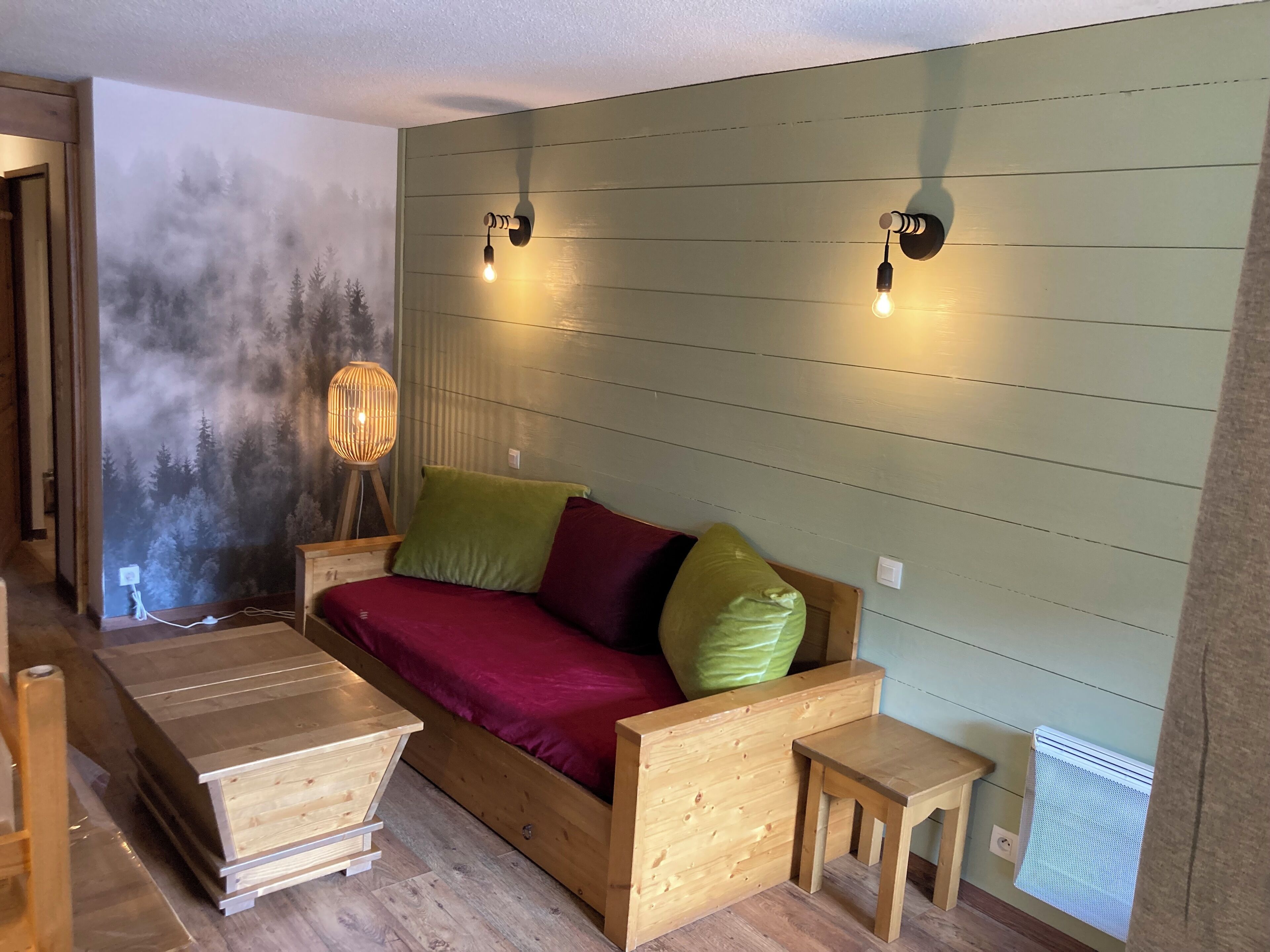 Et hyggeligt værelse med en seng, et lille bord og en lampe på væggen.