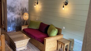 Une pièce confortable avec un lit, une petite table et une lampe fixée au mur.