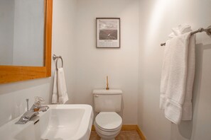 Une salle de bain avec un lavabo blanc, des toilettes et un tableau encadré représentant la Virginie-Occidentale accroché au mur.