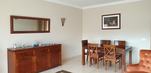 A dining area with a wooden cabinet, a glass table, and four wooden chairs.