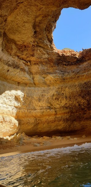 A natural rock formation with a cave entrance and a beach in the foreground. - A beautiful apartment in a fishing village. Algarve, Portugal (Mexilhoeira da Carregaçao)