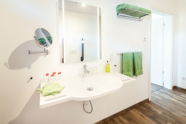 Un baño con lavamanos blanco, un espejo y una toalla verde.