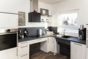 A modern kitchen with a built-in oven, a coffee maker, and a sink.