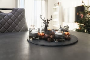 A table with a decorative arrangement including a reindeer figurine, candles, and pine cones.