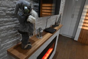 A room with a fireplace, a mounted television, and a decorative item resembling a bear on a wooden shelf.