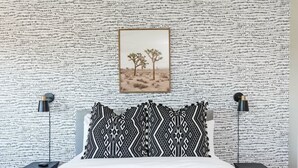 A bedroom with a patterned wall, a bed with black and white bedding, two bedside lamps, and a framed picture of trees. - Sereno- North Scottsdale- Private Pool & Games! (Scottsdale)