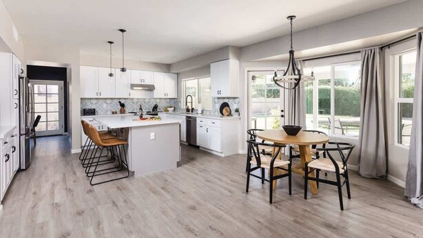 A modern kitchen with white cabinets, a central island, and a dining area with a round table and chairs. - Sereno- North Scottsdale- Private Pool & Games! (Scottsdale)