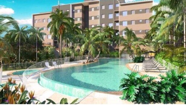 A modern hotel with a swimming pool surrounded by palm trees and greenery.
