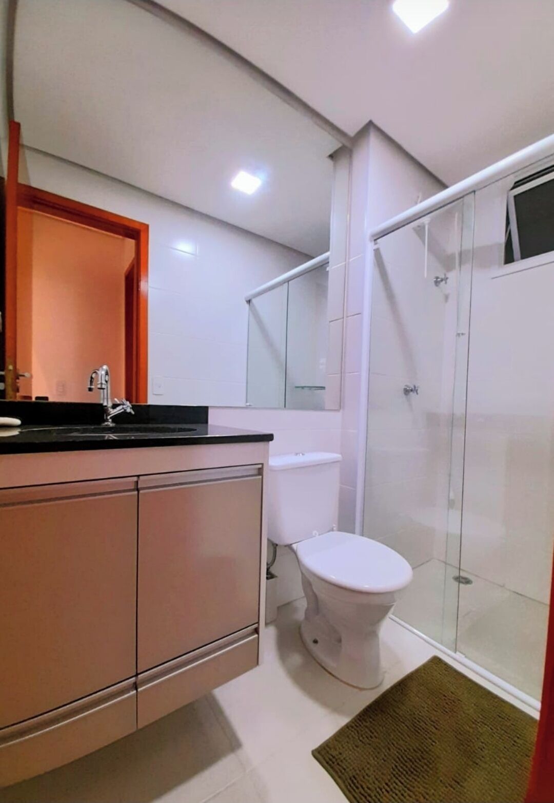A modern bathroom with a glass shower enclosure, a white toilet, and a vanity with a mirror.