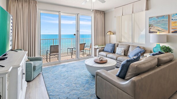 Ein Hotelzimmer mit Balkon, Deckenventilator, einer Couch, einem Couchtisch und Blick aufs Meer.