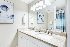 Un baño moderno con un espejo grande, dos lavamanos y una zona de ducha.