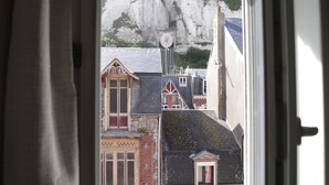 A view through a window with curtains, featuring buildings and a mountain in the background. - Villa 1900 "Jeanne", fully renovated, 100 meters from the beach (Le Tréport)