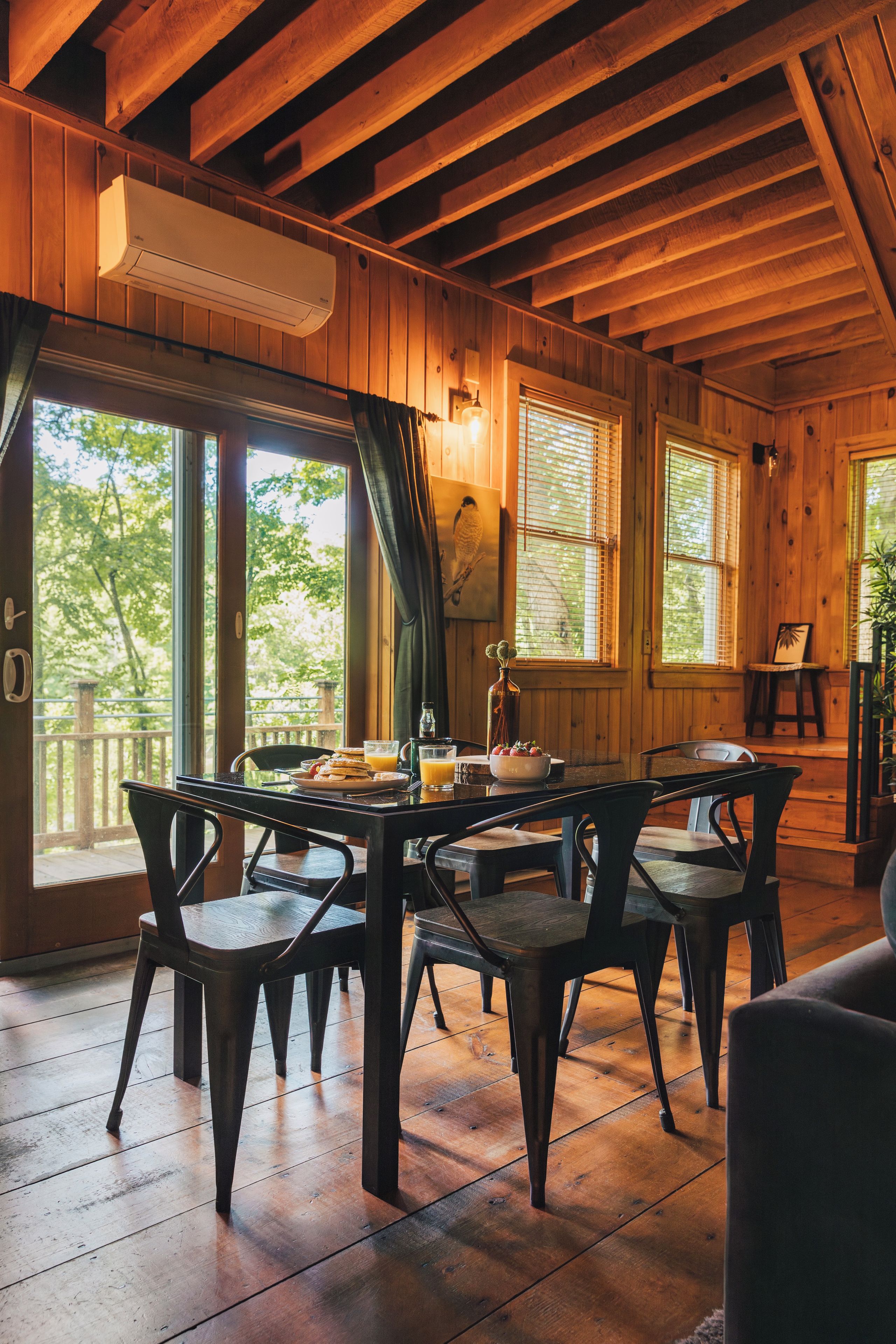 A wooden dining area with a table set for breakfast, including plates, glasses, and a pitcher.