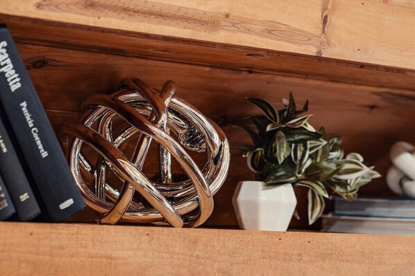 Une étagère en bois sur laquelle se trouvent une sphère métallique, une plante en pot et des livres.
