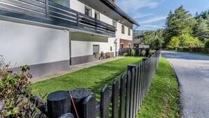 Una casa moderna de dos pisos con un balcón, césped cuidado y valla de madera.