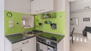 Una cocina moderna con armarios blancos, salpicadero verde y horno empotrado.