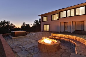 A stone patio with a fire pit and hot tub, surrounded by a stone wall. - Canyon View House w/ hot tub, game room, views, and more! (Oakhurst)