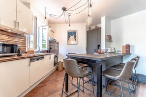 A modern kitchen with white cabinets, a central island with bar stools, and pendant lighting.