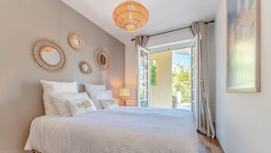 A bedroom with a large bed, a ceiling light, and a view of the outdoors.