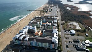 Ilmakuva rannikolla sijaitsevasta hotellista, jossa on useita rakennuksia, ranta ja laituri.