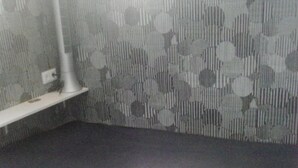 Une pièce avec un lit, une lampe sur pied et un papier peint à motifs.