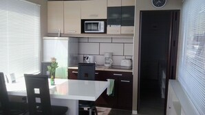Une cuisine compacte comprenant une table à manger, des chaises, une horloge et un four à micro-ondes.