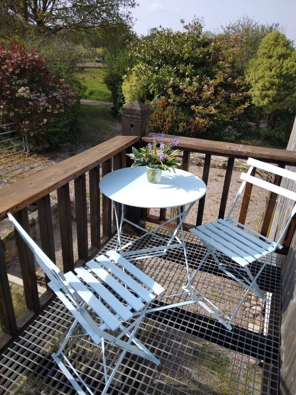 A small outdoor seating area with a round table and two white chairs, surrounded by a wooden deck and a metal railing. - Quiet 1st floor apartment with balcony and patio, 18 km from the sea (Landebia frankreich)