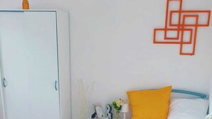 Een slaapkamer met een bed, nachtkastje, kledingkast en een wanddecoratie.