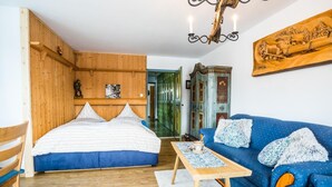 Une pièce avec un lit en bois, un canapé bleu, une table basse en bois et un lustre.