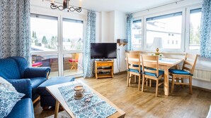 Un salon comprenant un canapé, un téléviseur, une table à manger en bois et des chaises.