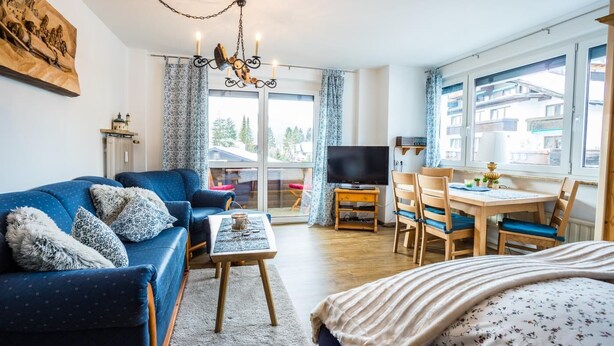 Un salon moderne comprenant un canapé, une table basse, un téléviseur et un coin repas avec des chaises et une table.