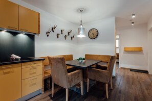 A modern kitchen with wooden cabinets, a black countertop, and a dining area with a table and chairs.