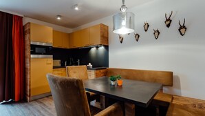 Een moderne keuken met gele kastjes, een eettafel met stoelen, een hanglamp en dieren schedels aan de muur.