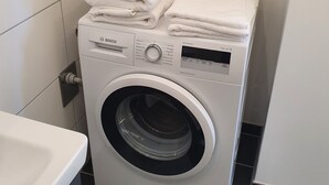 Een voorlader wasmachine met witte handdoeken er bovenop gestapeld.