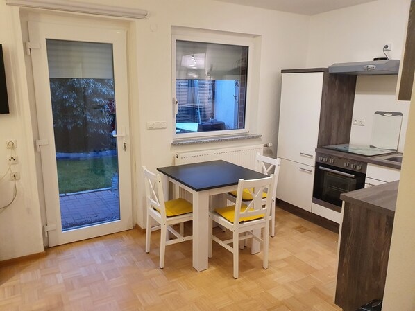 Eine kleine Küche mit Esstisch und Stühlen, einem Fenster und einem eingebauten Backofen.