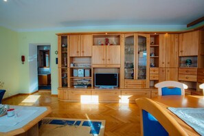 A living room with a wooden cabinet, a television, and a dining table.