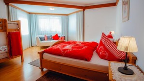 Een gezellige slaapkamer met een houten bed, een slaapbank en een stapelbed.