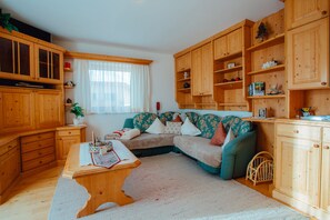 A cozy living room with wooden furniture, a sofa, a coffee table, and built-in wooden cabinets.